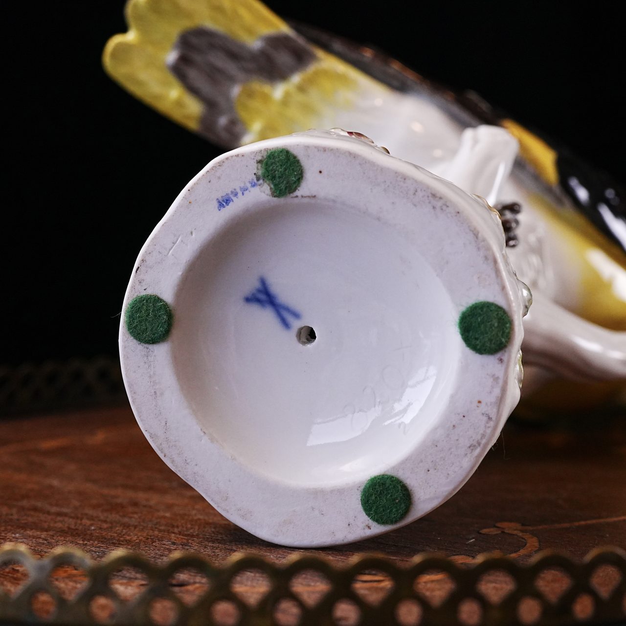 Underside of the Meissen Golden Oriole figurine showing the blue underglaze crossed swords mark, impressed model and painter numbers, and green felt pads